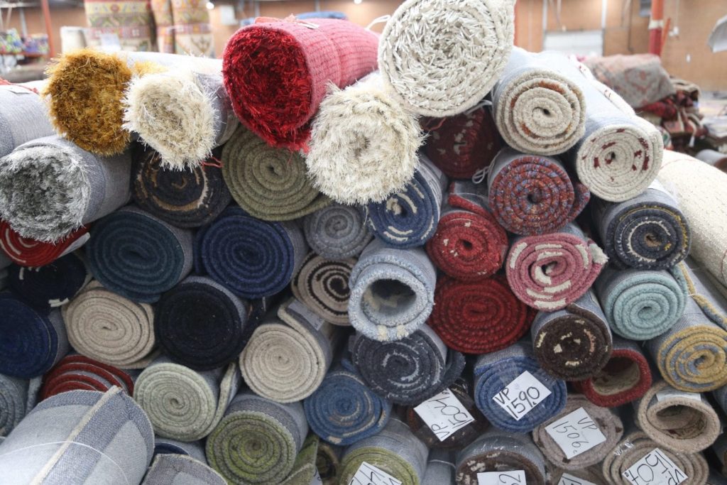 an image of different colored rugs rolled up in a pile