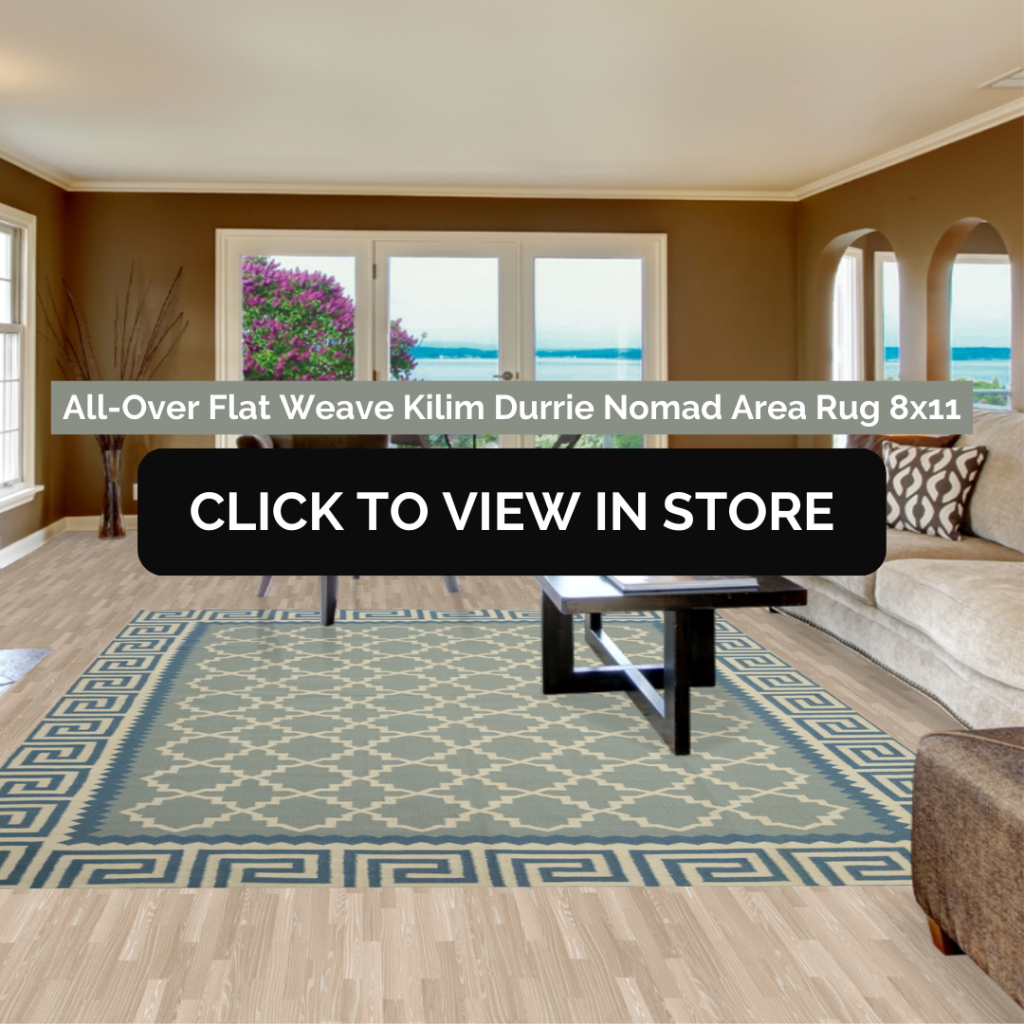 Spacious living room featuring an 8x11 All-Over Flat Weave Kilim Durrie Nomad area rug in soft blue and cream hues, displaying an intricate geometric pattern framed by a bold border. The rug complements the room's serene atmosphere, enhanced by natural light streaming through large windows overlooking a garden. Neutral-toned furniture and a sleek black coffee table complete the modern and cozy setting.