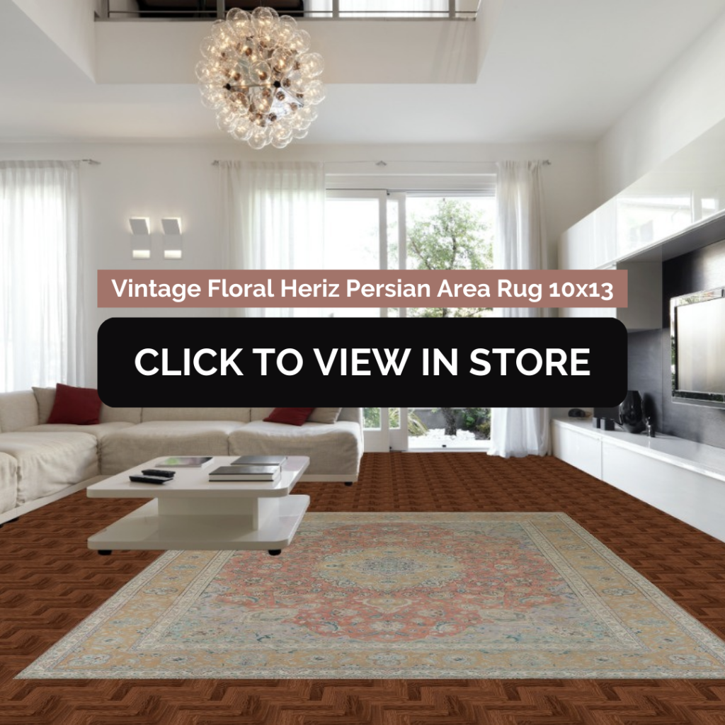 Elegant living room featuring a 10x13 Vintage Floral Heriz Persian area rug with intricate floral motifs in warm red and beige hues. The rug rests on rich parquet wood flooring, complementing a white modern sectional sofa with red throw pillows and a sleek white coffee table. Large windows and contemporary decor complete the sophisticated ambiance.