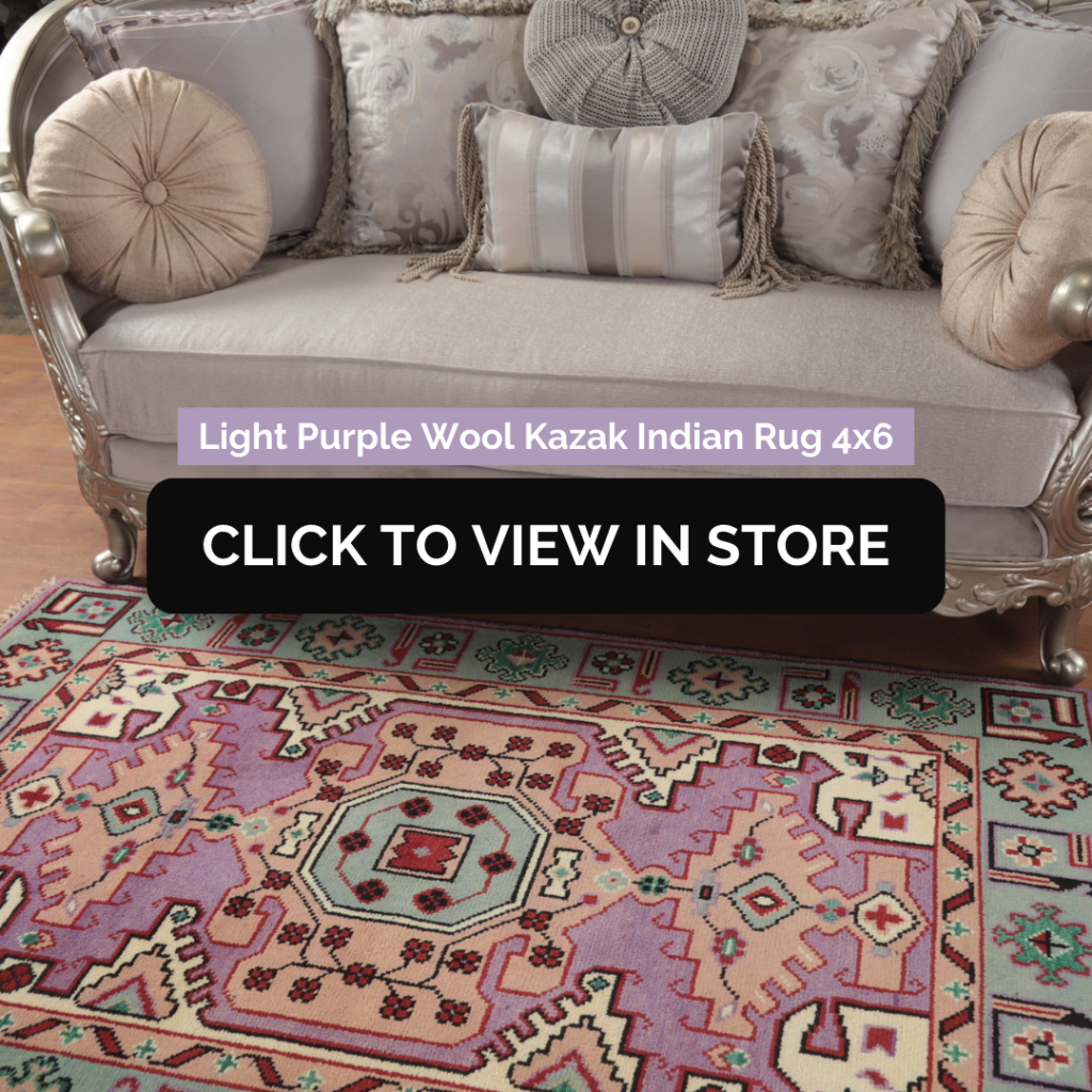 Light Purple Wool Kazak Indian Rug (4x6) showcased in a luxurious living space. The rug has a pastel purple and pink geometric pattern with intricate details, adding a vintage charm. It is placed beneath an elegant silver-framed sofa adorned with plush decorative pillows in neutral tones. The setting exudes a classical and refined aesthetic. The image includes text: "Light Purple Wool Kazak Indian Rug 4x6" and a call-to-action button: "CLICK TO VIEW IN STORE."