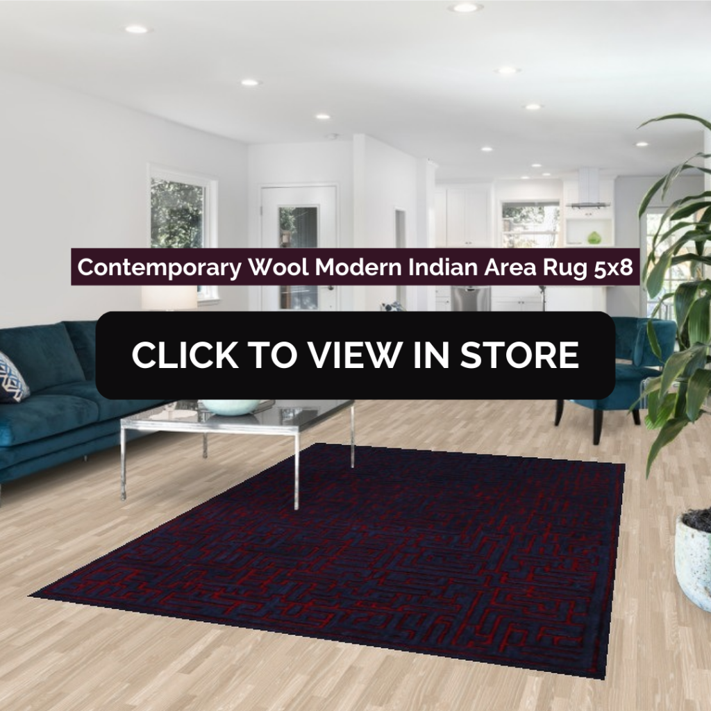 Contemporary Wool Modern Indian Area Rug (5x8) displayed in a modern open-concept living room. The rug has a dark navy blue base with an abstract red geometric pattern, complementing the minimalist decor with a sleek glass coffee table, a deep blue sectional sofa, and white kitchen cabinetry in the background. The image includes text: "Contemporary Wool Modern Indian Area Rug 5x8" and a call-to-action button: "CLICK TO VIEW IN STORE."