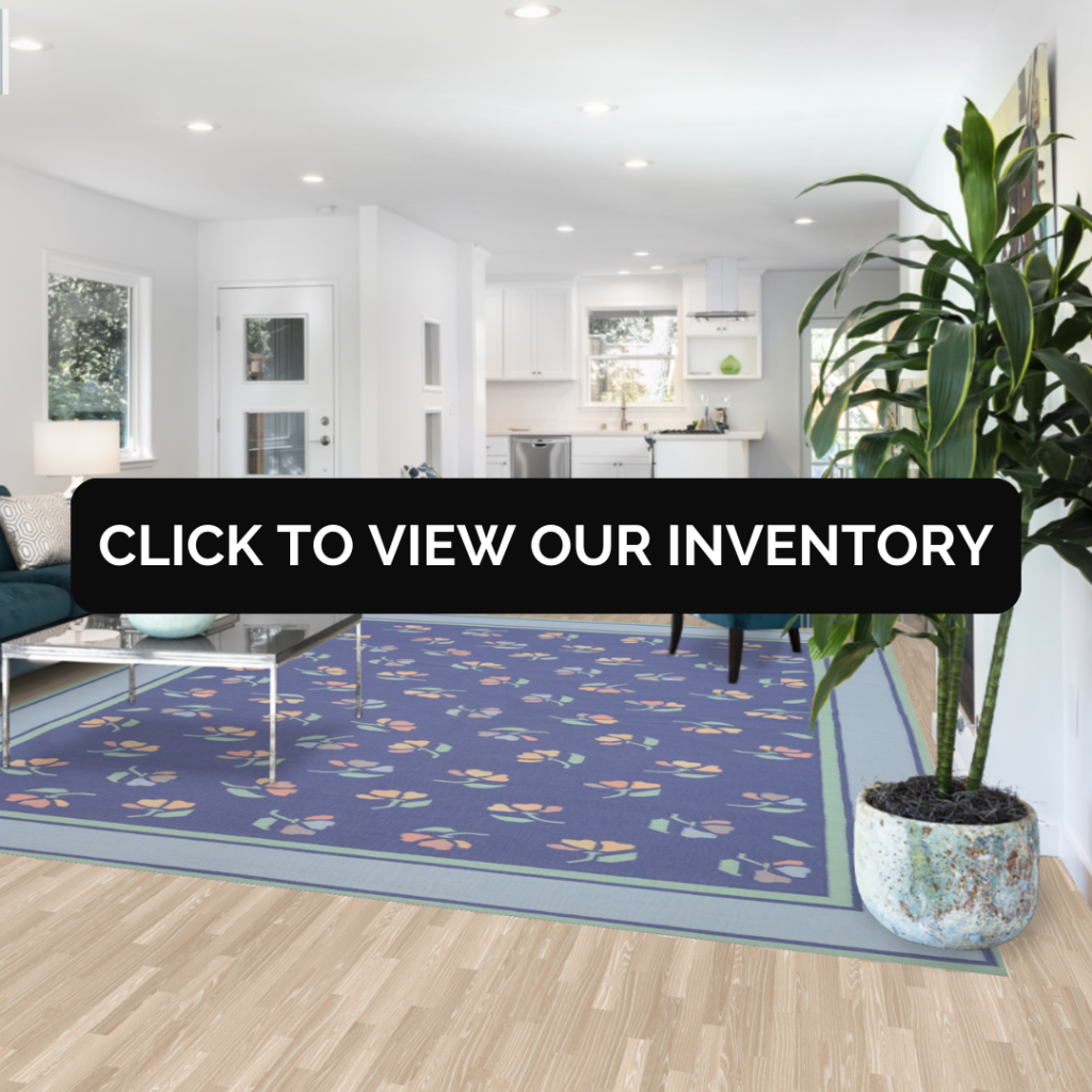 A minimalist and elegant living room features a Floral Flat Weave Kilim Durrie Area Rug (9x12) with a navy blue background and delicate floral designs in pastel shades. The rug lies beneath a glass coffee table, blending harmoniously with a white sofa and modern decor.