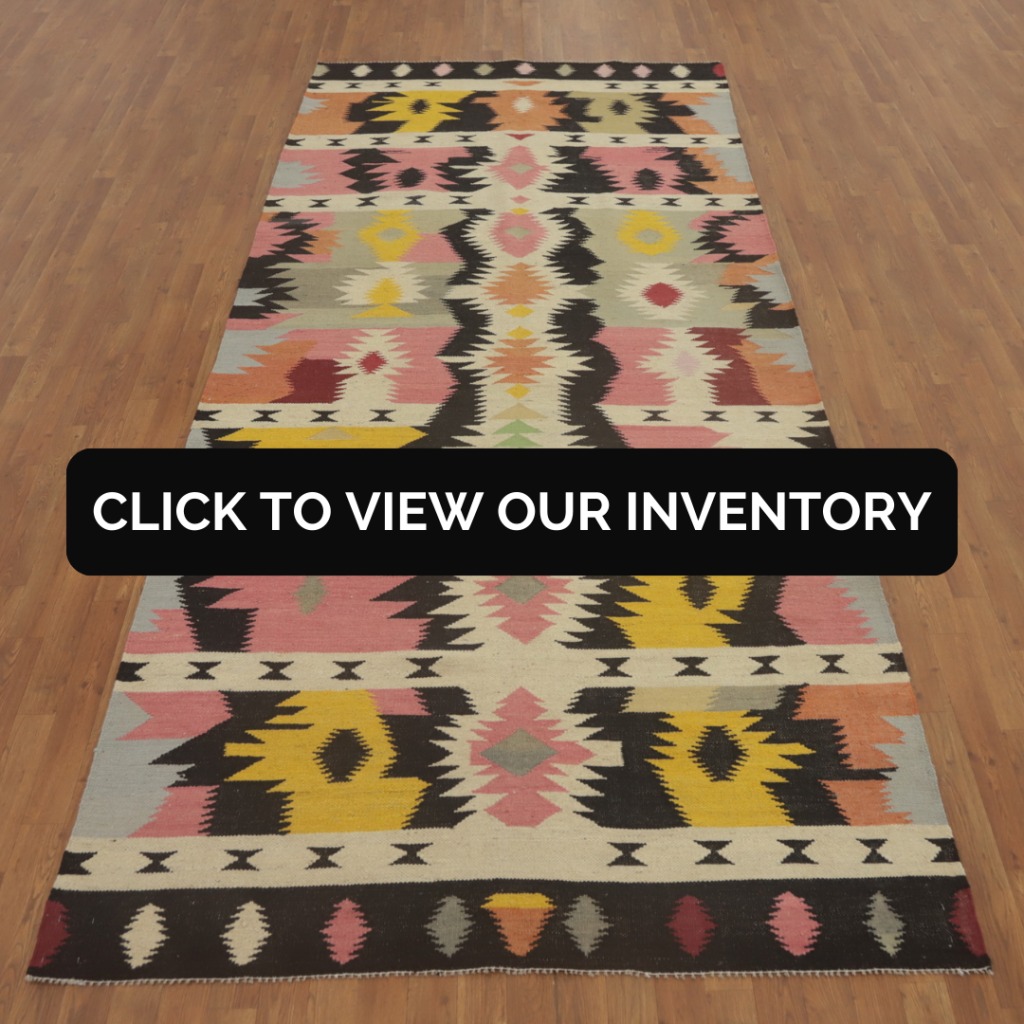 Tribal Kilim Oriental Area Rug 5x12
A colorful tribal kilim rug with bright pinks, yellows, and blacks is laid out on a wooden floor in a minimal studio setting. The repeating diamond and chevron shapes add dynamic visual interest.