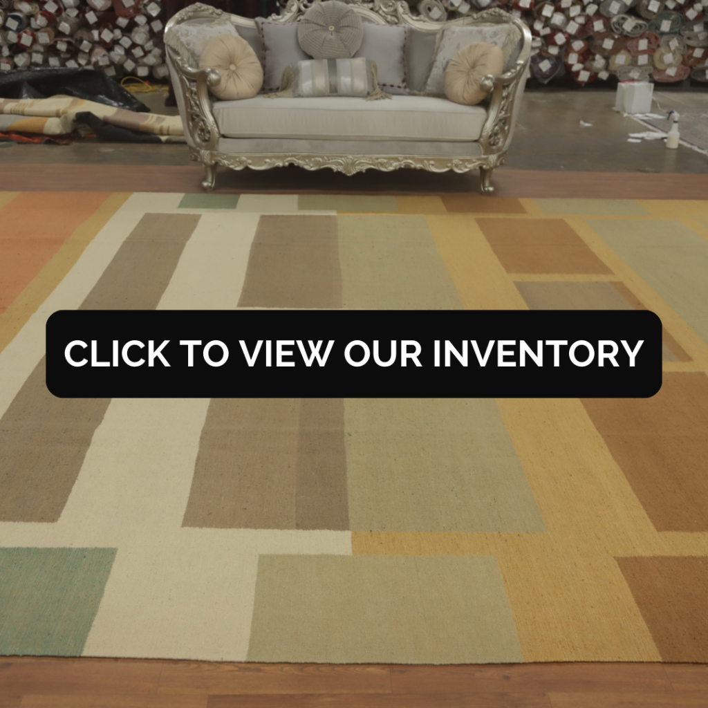 Vegetable Dye Kilim Modern Rug
A large modern Kilim rug in muted earth tones, including beige, tan, and green, is spread beneath an ornate silver sofa in a warehouse setting. The geometric block pattern and natural vegetable dyes give it a minimalist and rustic look.