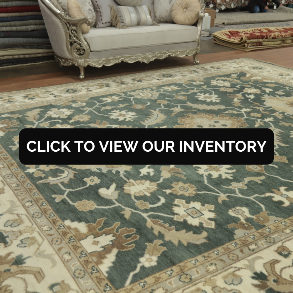 All-Over Floral Green Oushak Indian Large Rug 12x15
A large green Oushak rug with an all-over floral design sits beneath a regal ivory and silver couch in a rug showroom. The surrounding area displays folded rugs and warm lighting.