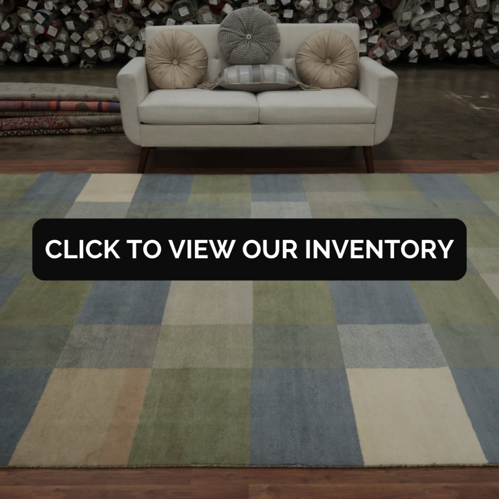 A beige sofa with round pillows displayed behind a muted checkered rug in soft blue, green, and tan shades.