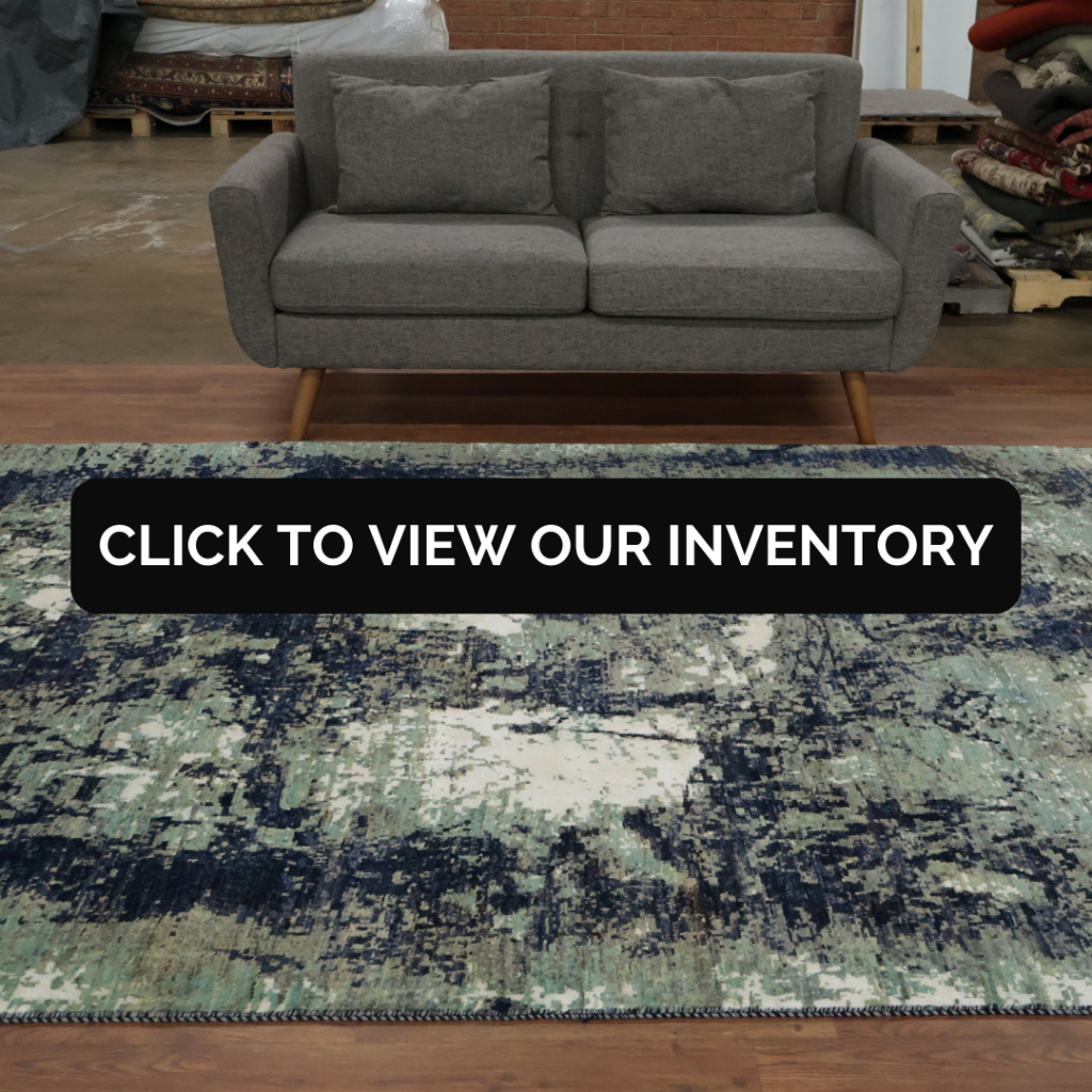 A gray sofa sits behind a distressed-style rug in blue, cream, and teal tones with an abstract pattern.