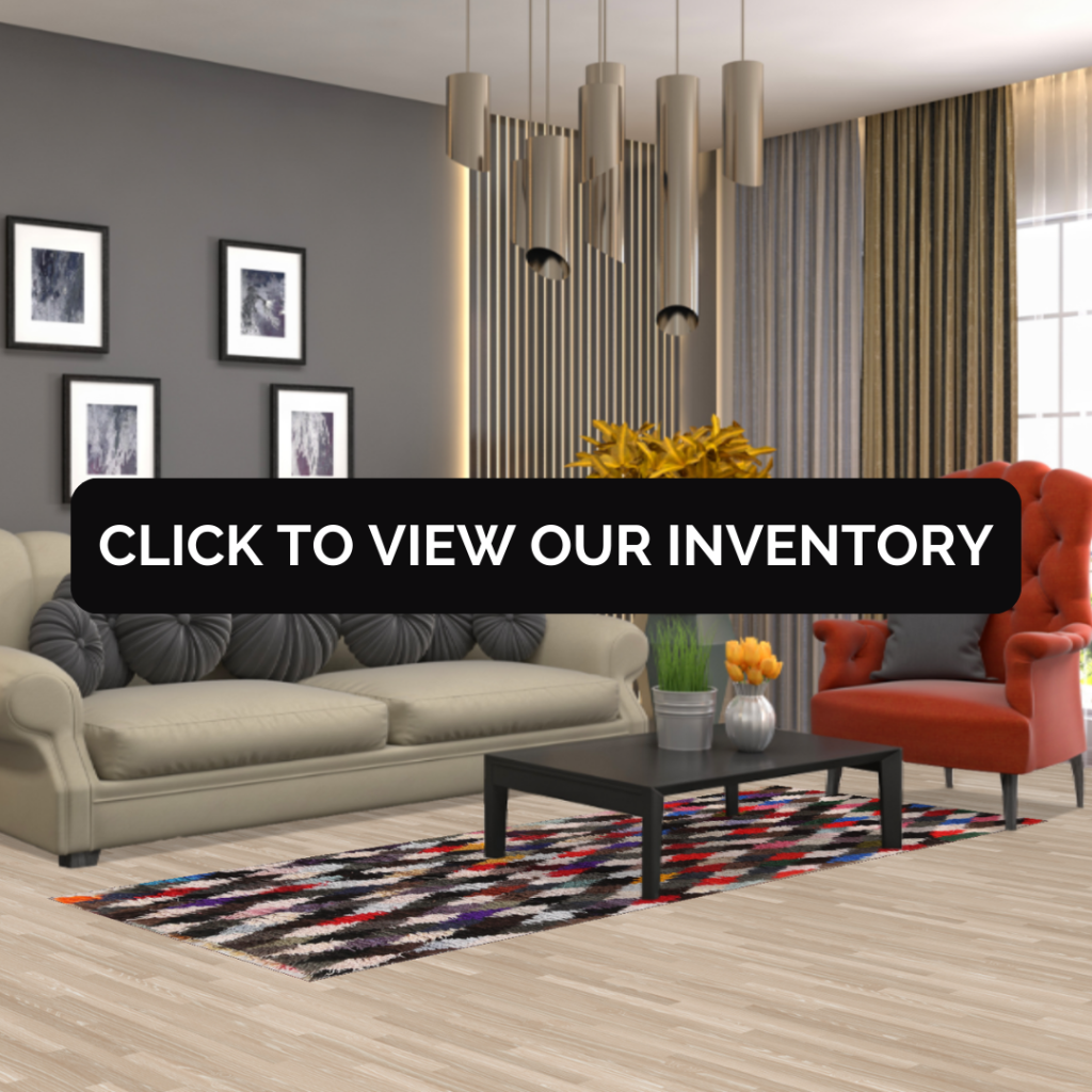 A colorful patterned rug with red, black, white, and tan diamond shapes styled beneath a beige sofa and red chair in a modern living room.
