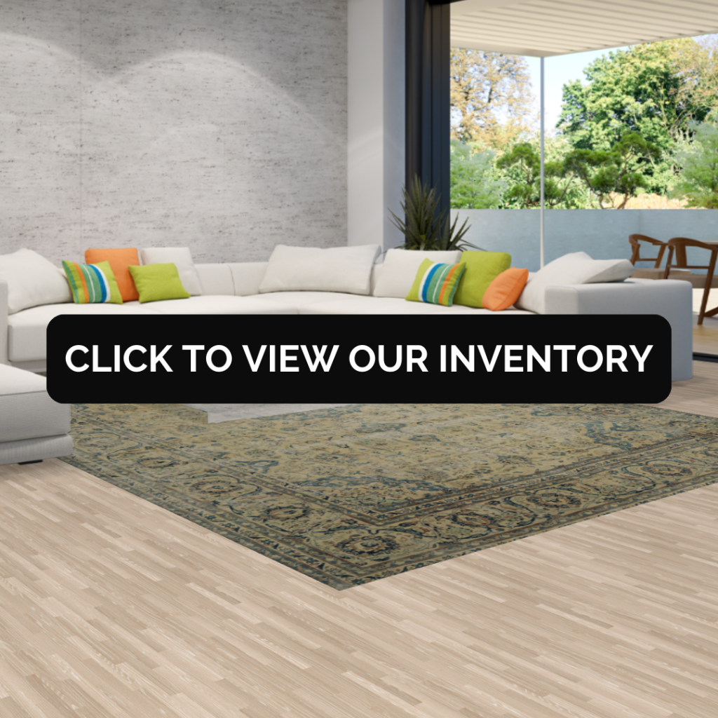 A modern living room with a large white sectional and colorful pillows, featuring a muted green patterned rug beneath a black banner that reads “Click to View Our Inventory.”