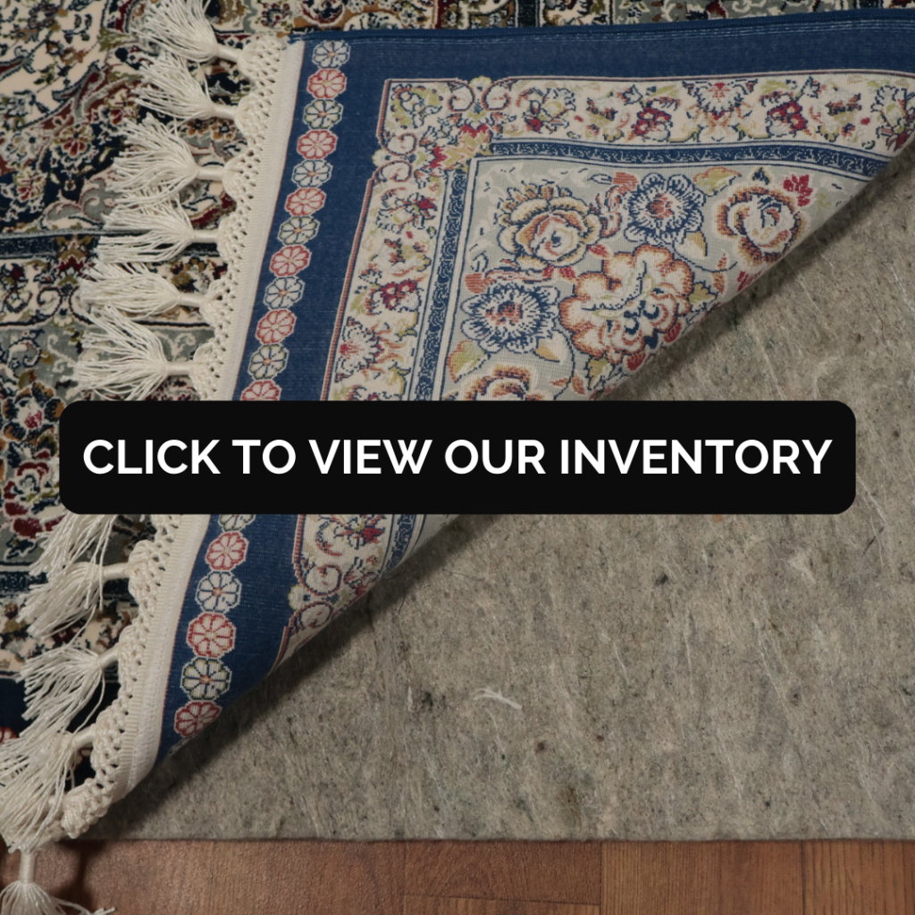A close-up of a traditional rug corner with blue and floral designs folded back, displaying the backing, with a black banner that says “Click to View Our Inventory.”