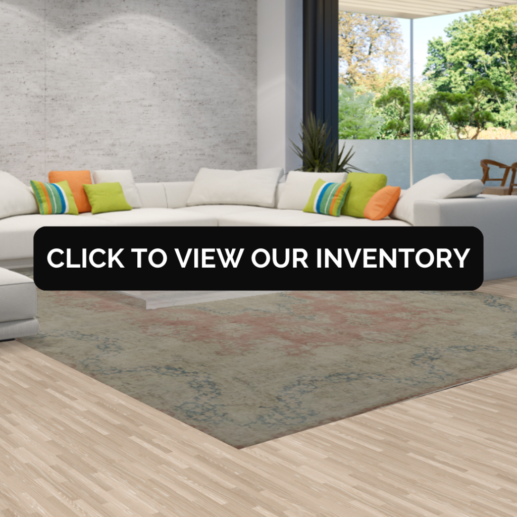 A stylish living room with gray walls and modern decor, featuring a richly patterned green and red rug with a black banner that says “Click to View Our Inventory.”
