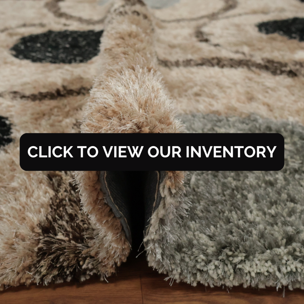 A close-up of a fluffy beige and gray shag rug rolled over, highlighting its soft texture, with a black banner that says “Click to View Our Inventory.”