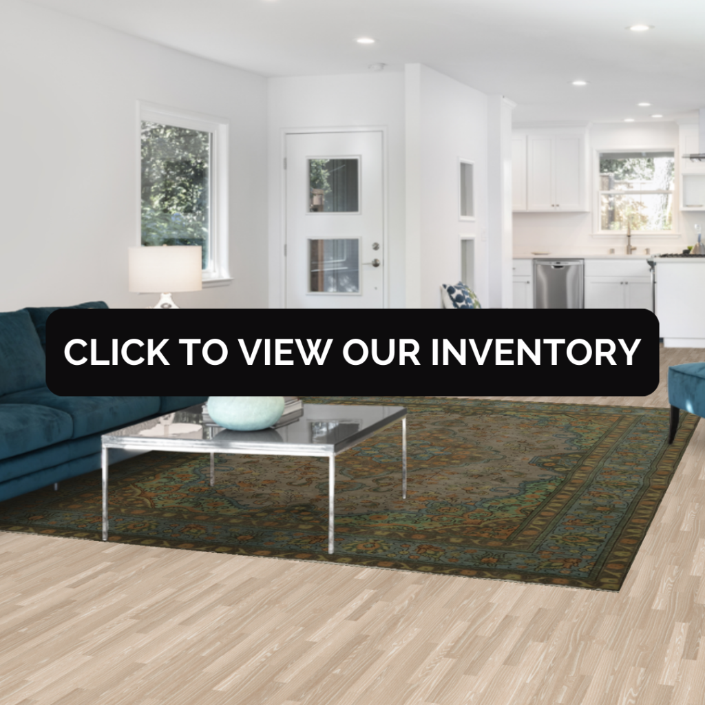 A stylish living room with gray walls and modern decor, featuring a richly patterned green and red rug with a black banner that says “Click to View Our Inventory.”