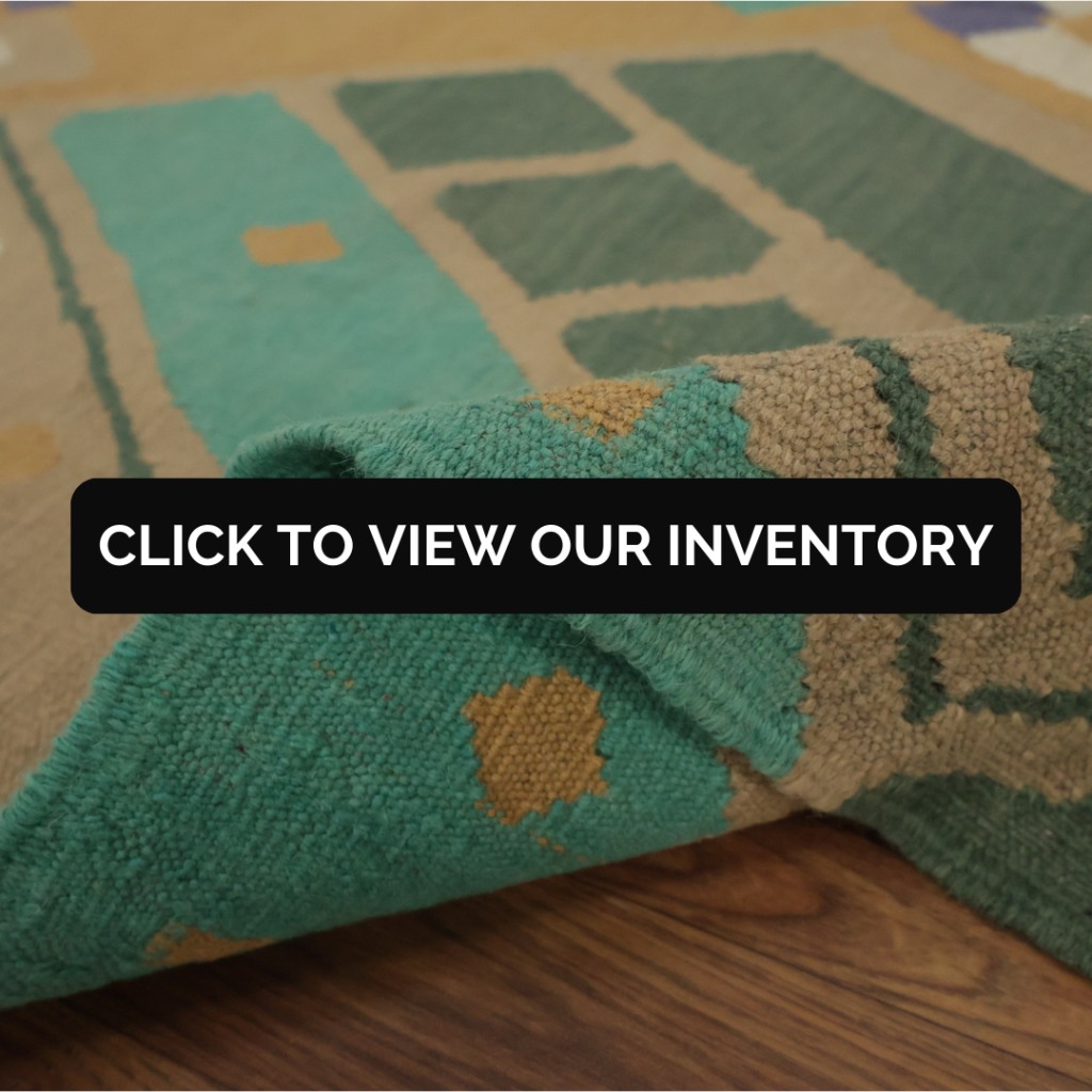 A close-up of a woven rug in earthy green and tan tones, with one corner folded over to show the texture. Text overlay reads “Click to view our inventory.”