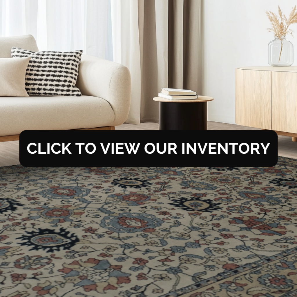 A cream and blue floral rug with intricate patterns, placed under a beige sofa in a modern, light-filled living room. Text overlay reads “Click to view our inventory.”