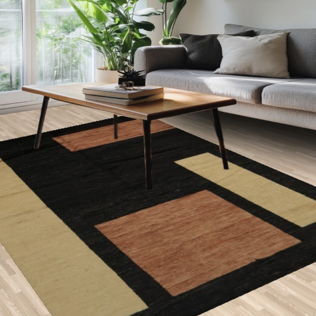 A close-up view of a living room showcasing a wooden coffee table and gray sofa on a large rug with bold rectangular shapes in tan, rust, and black tones.