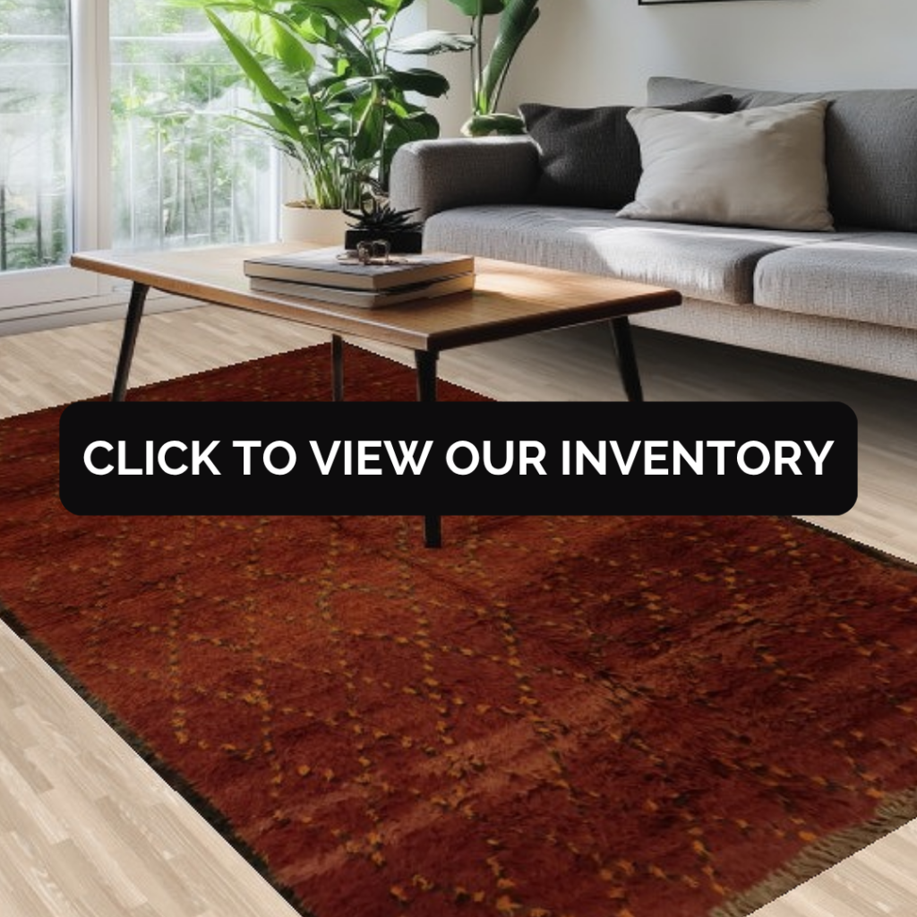 A cozy contemporary space with a gray sofa and wooden coffee table on a deep rust-colored rug with a subtle diamond pattern. Large windows bring in natural light beside lush green plants.