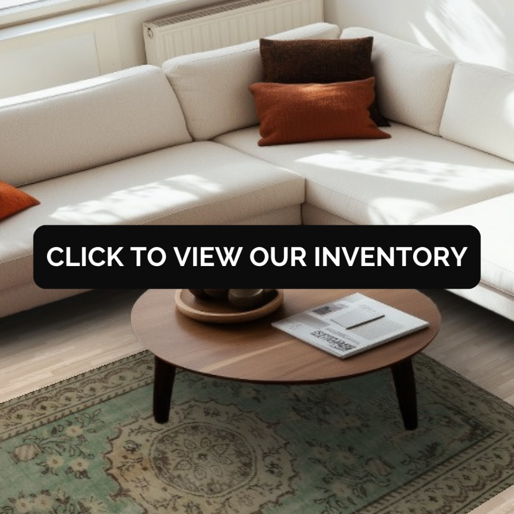 A bright living space with a cream sectional sofa, orange throw pillows, and a round wooden coffee table resting on a mint-green vintage rug with intricate floral motifs.