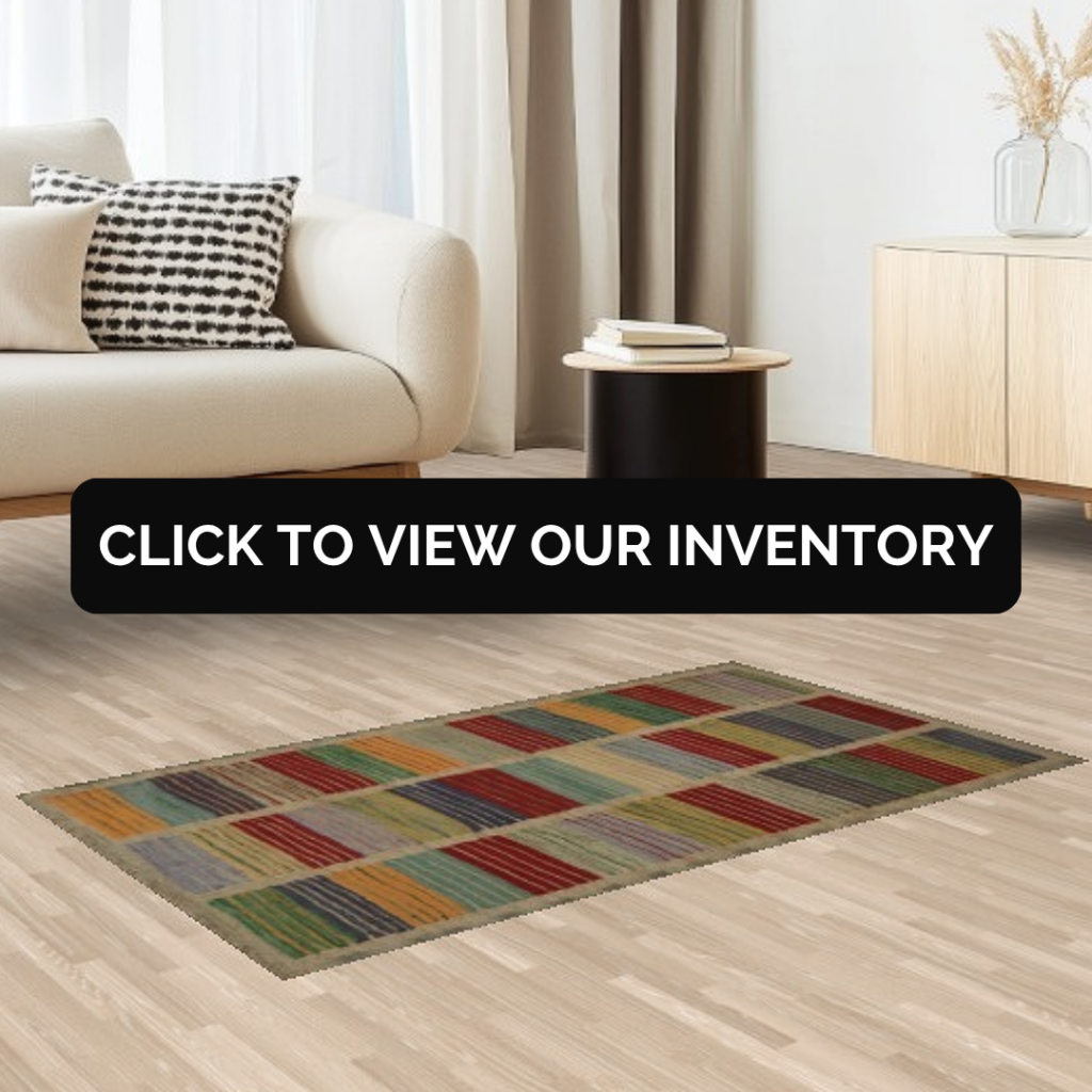 A modern living room with a light beige sofa, a black-and-white patterned pillow, and a colorful geometric rug featuring red, green, yellow, and blue rectangles. A black side table holds books beside a light wood console.