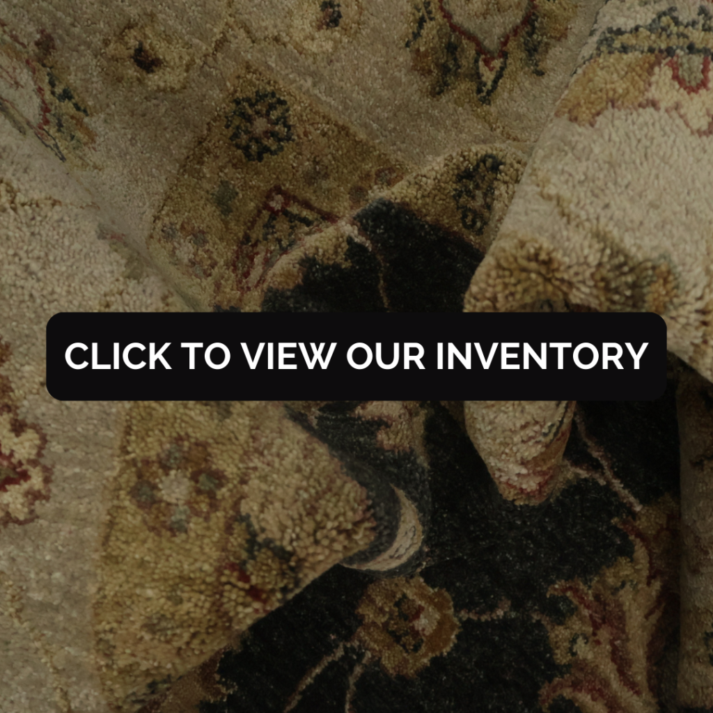 A close-up view shows a thick, textured rug folded over itself, revealing detailed floral and geometric motifs in beige, tan, and dark brown tones. The fibers appear plush and worn, emphasizing the rug’s craftsmanship and age. A black “CLICK TO VIEW OUR INVENTORY” button sits across the center.