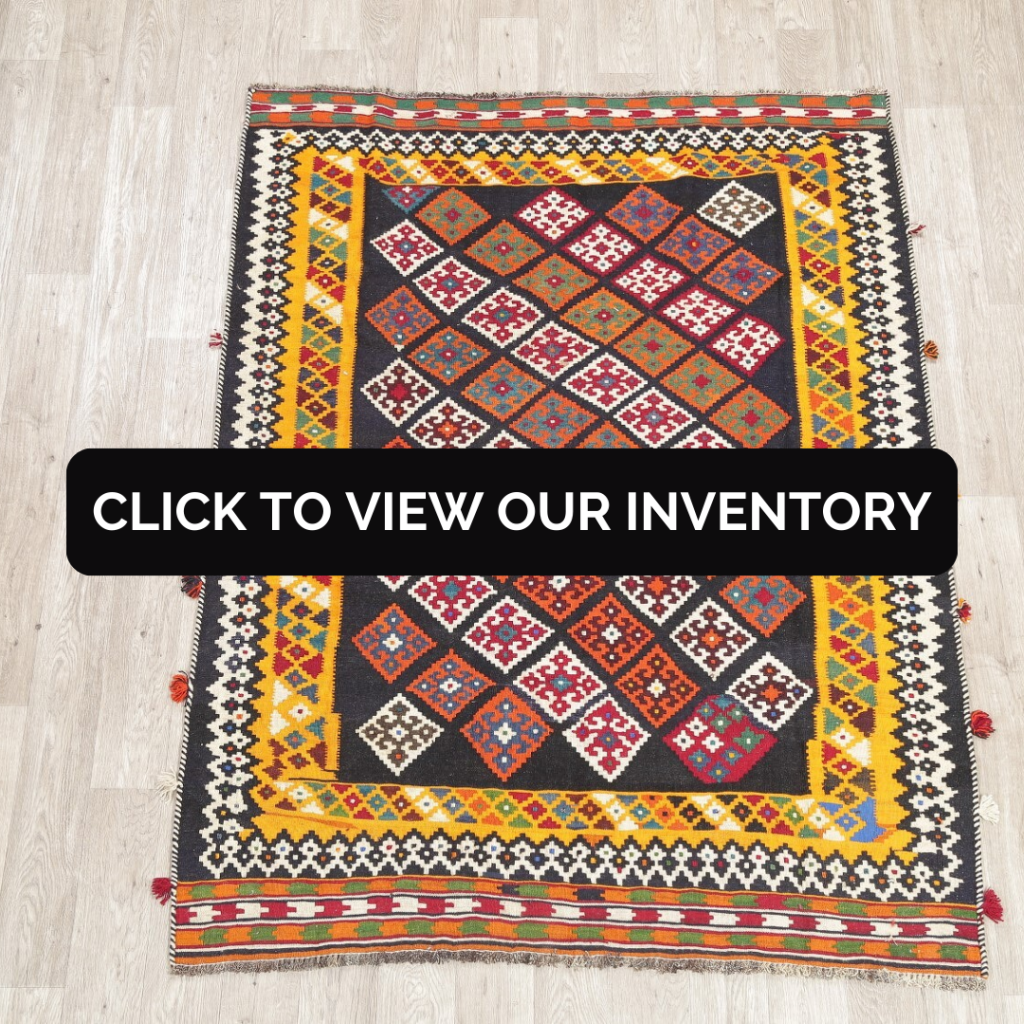 A vibrant flatweave rug with bold geometric diamonds in red, orange, turquoise, white, and yellow fills the frame. The rug’s patterned border adds additional contrast and detail. A black “CLICK TO VIEW OUR INVENTORY” banner overlays the middle.