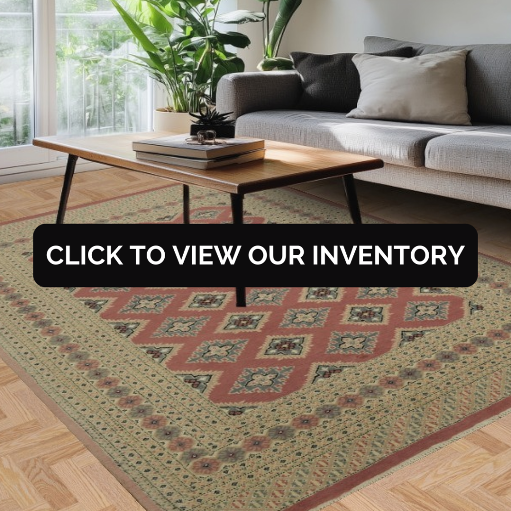 A modern living room features a gray sofa with neutral pillows beside a light wood coffee table. A large geometric rug in muted red, sage green, and tan fills the floor, adding texture and pattern. A black “CLICK TO VIEW OUR INVENTORY” button appears across the middle.