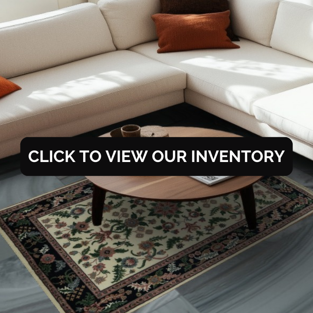 A bright living room showcases a cream sectional sofa paired with a round wooden coffee table. A dark green traditional rug with subtle floral detailing anchors the seating area. A black “CLICK TO VIEW OUR INVENTORY” button is centered over the image.