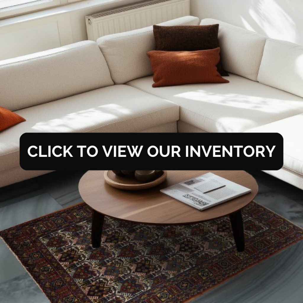 A cream sectional sofa is arranged around a round wooden coffee table holding a tray and magazine. Beneath the table is a traditional floral rug with a light background and dark border. A black “CLICK TO VIEW OUR INVENTORY” button overlays the center of the scene.