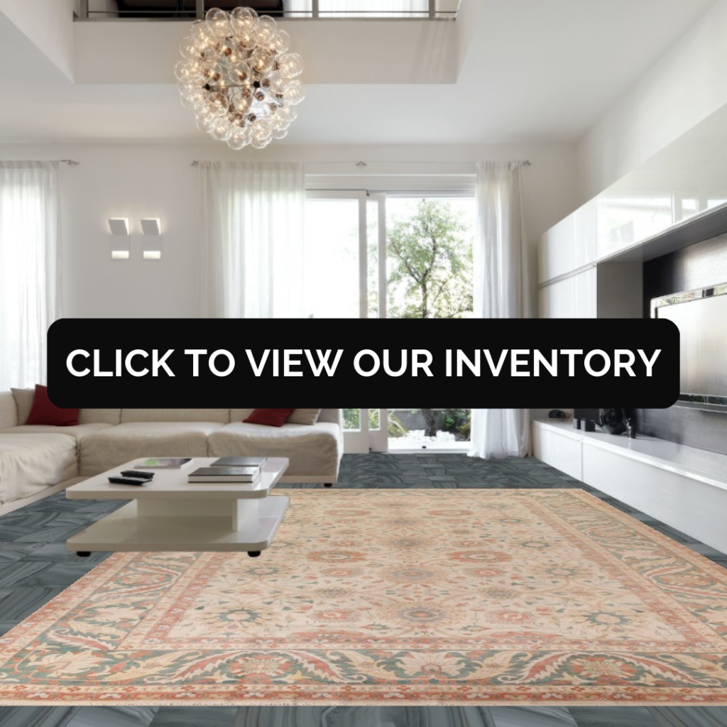 Modern living room with a large, soft-toned rectangular area rug centered beneath a low coffee table. The space includes white furniture, tall windows with sheer curtains, and contemporary lighting.