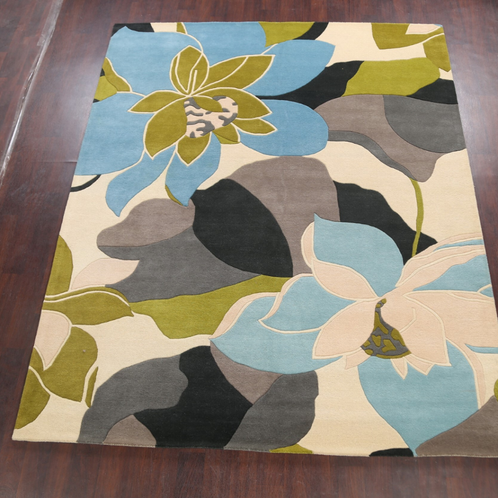 Full view of a square floral area rug featuring oversized flowers in blue, green, cream, and gray. The rug is centered on a hardwood floor, emphasizing its contemporary botanical design.