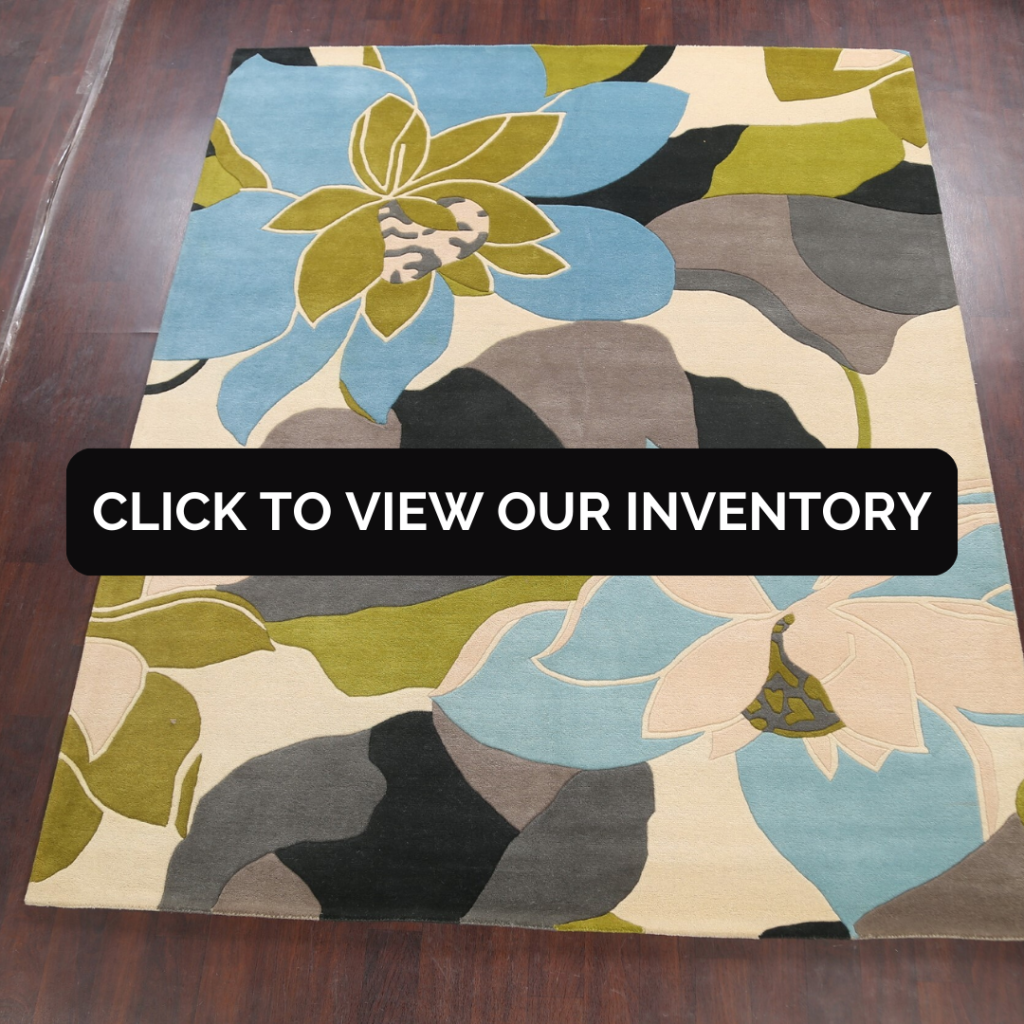 Square area rug with a bold, modern floral design in shades of blue, green, cream, and gray. The rug is displayed flat on a dark hardwood floor, highlighting its large-scale pattern.