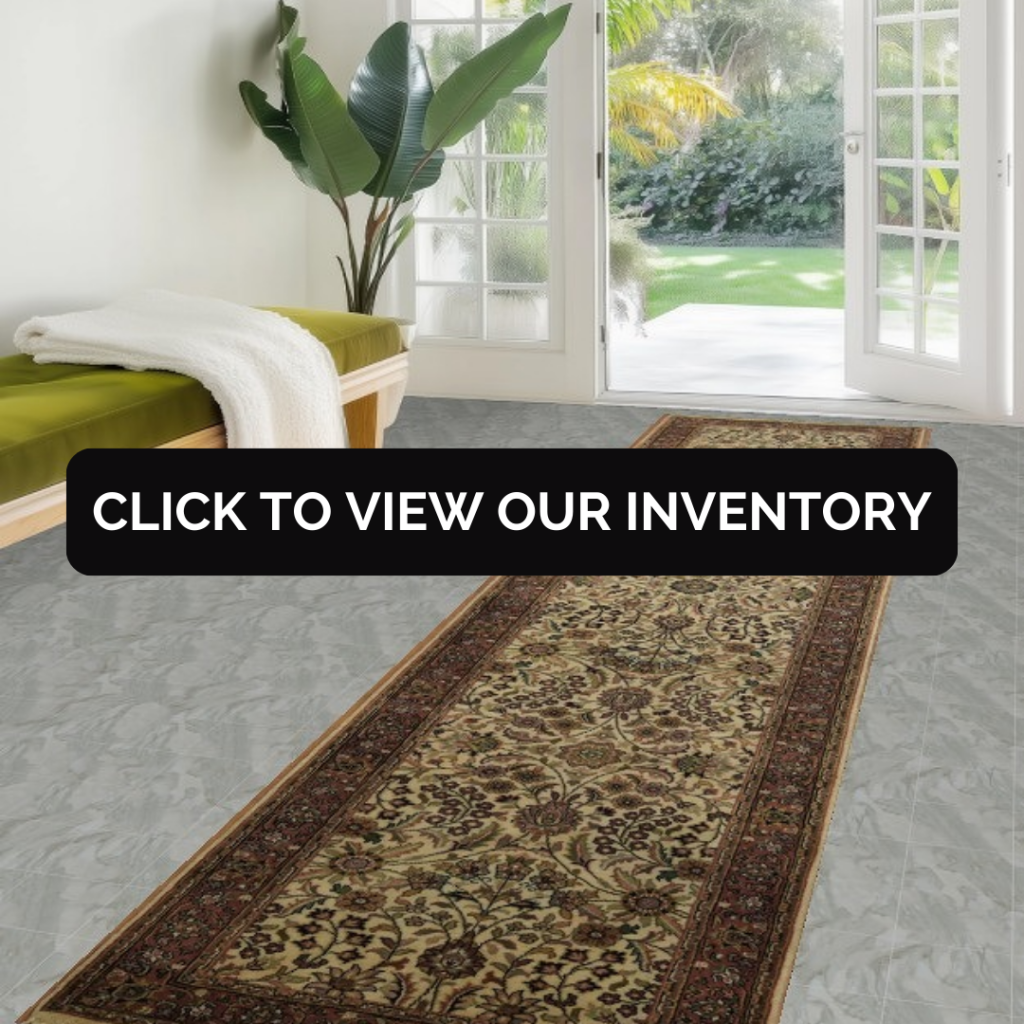 A bright entryway features a wooden bench with a green cushion and a folded white throw beside tall glass doors opening to a garden. A long runner rug with a beige floral pattern and dark red border stretches across the tiled floor. A black “CLICK TO VIEW OUR INVENTORY” button is centered over the scene.