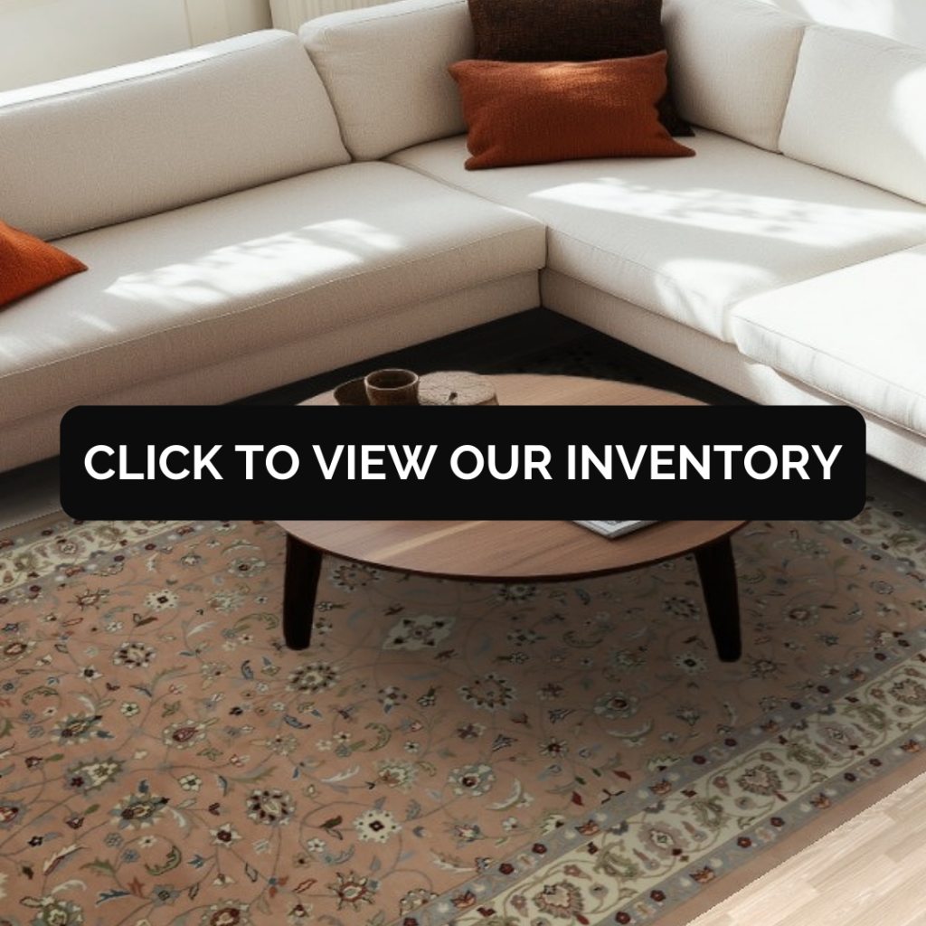 “White sectional sofa with accent pillows surrounding a round wood coffee table on a floral patterned area rug. Black button reads ‘Click to View Our Inventory.’”