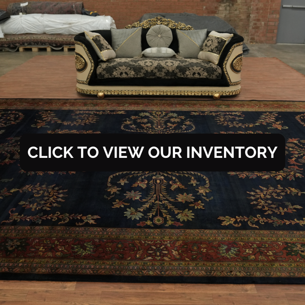 An ornate black and gold sofa with decorative pillows sits behind a dark blue patterned rug featuring floral motifs and a red border. A black banner across the center reads, “CLICK TO VIEW OUR INVENTORY.”
