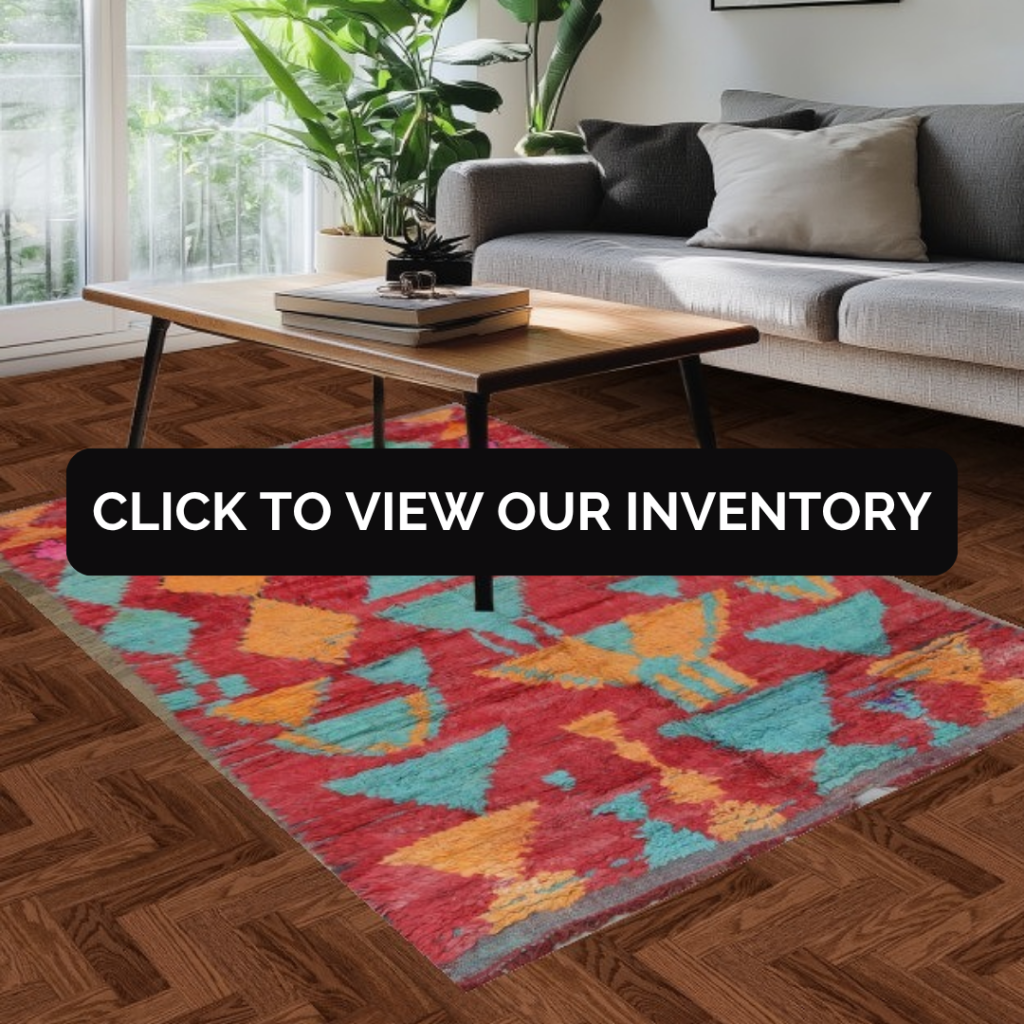 A bright living room with a gray sofa, wooden coffee table, and large window, featuring a bold abstract rug in red, teal, and yellow tones. A black banner across the center reads “Click to view our inventory.”