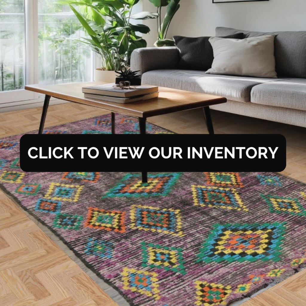 A modern living room with a gray sofa, wooden coffee table, and plants by a window, featuring a colorful rug with bold geometric patterns in purple, teal, orange, and yellow. A black banner across the center reads “Click to view our inventory.”