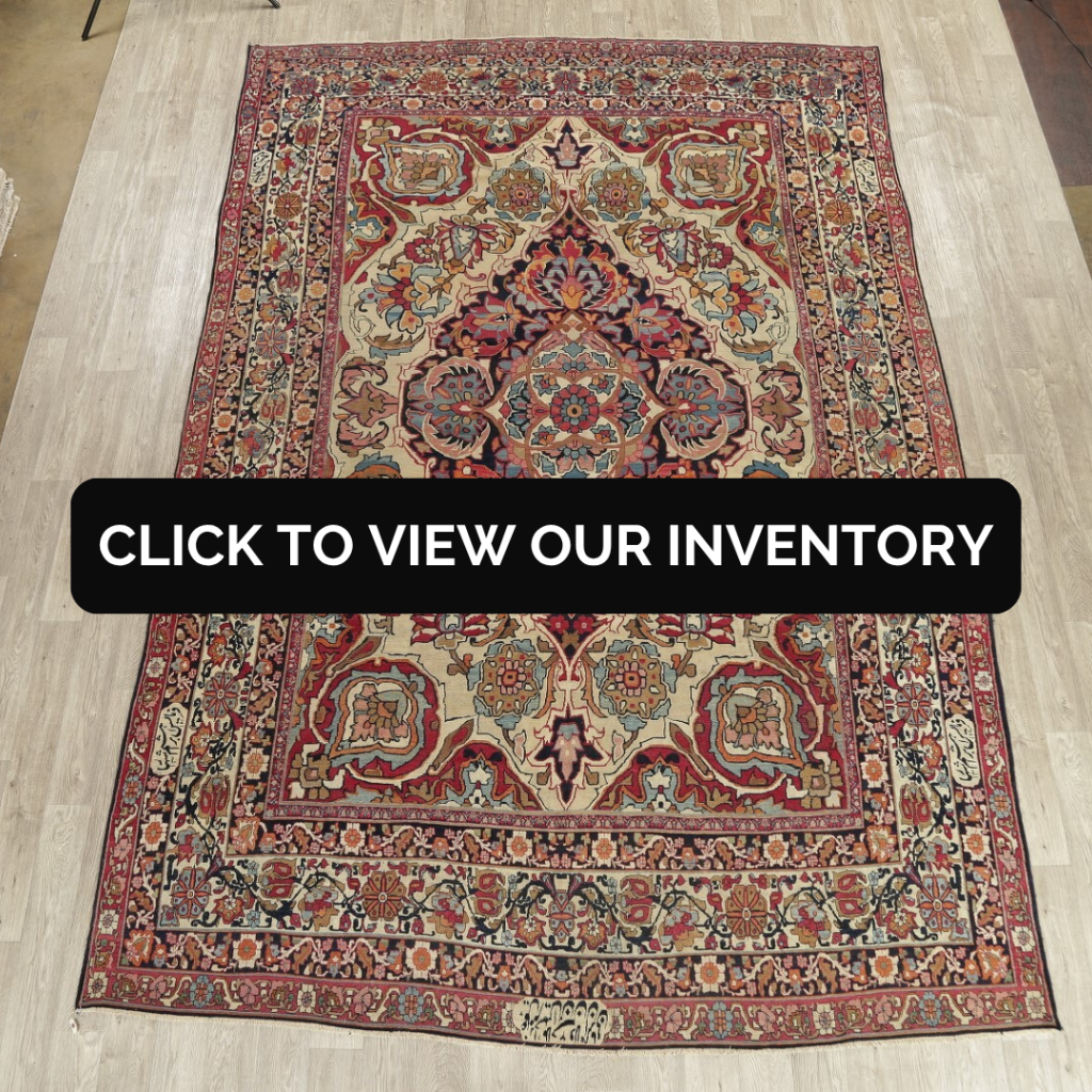 A detailed traditional rug with a central medallion and ornate floral motifs in red, navy, and cream tones, laid out on a light wood floor. A black banner across the center reads “Click to view our inventory.”